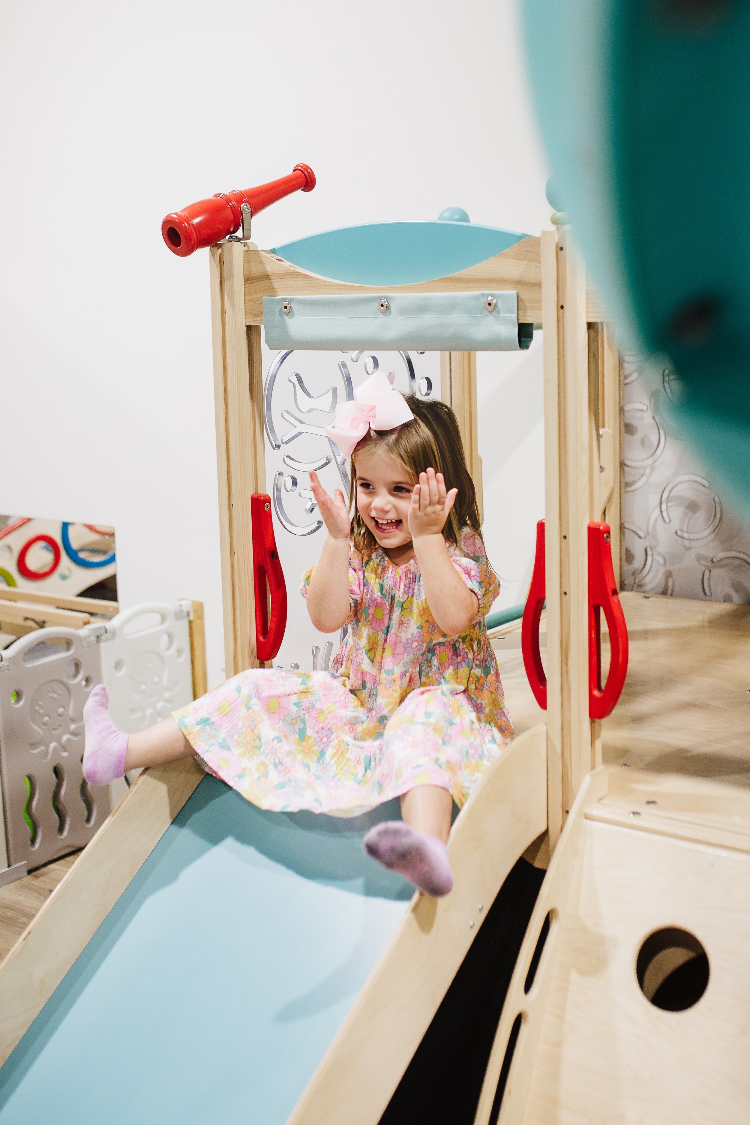 A child smiling while playing on a slide at Little Peaches.